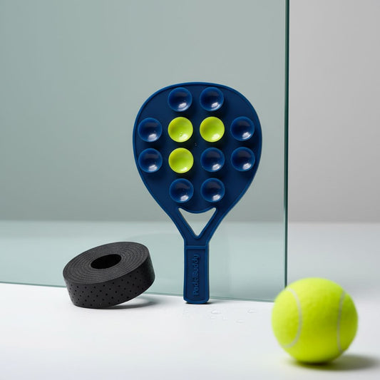 Starry Night PadelBuddy with green buttons, black tape roll, and yellow tennis ball on a reflective surface.